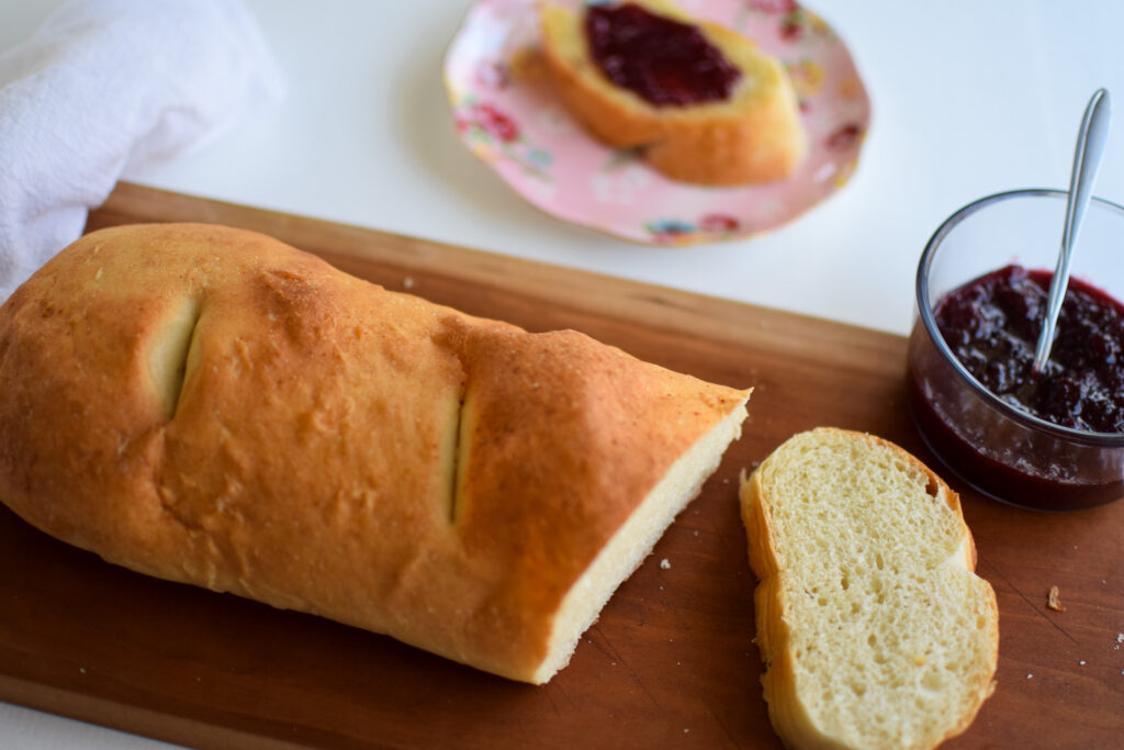 loaf of bread cut on a cutting board with a bowl of jelly