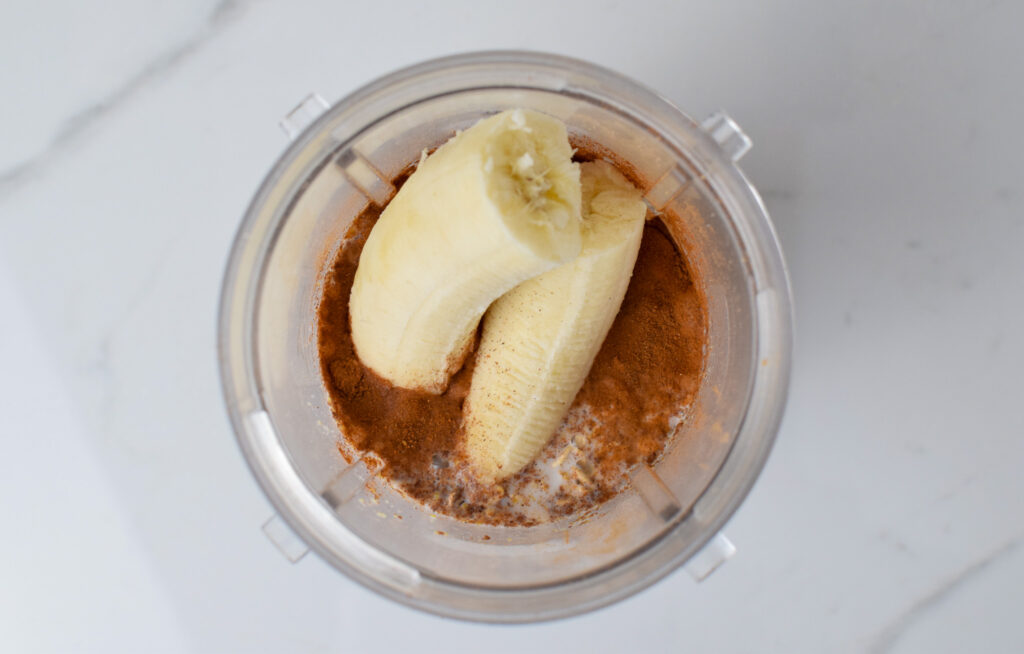 top view of open blender with bananas and cinnamon