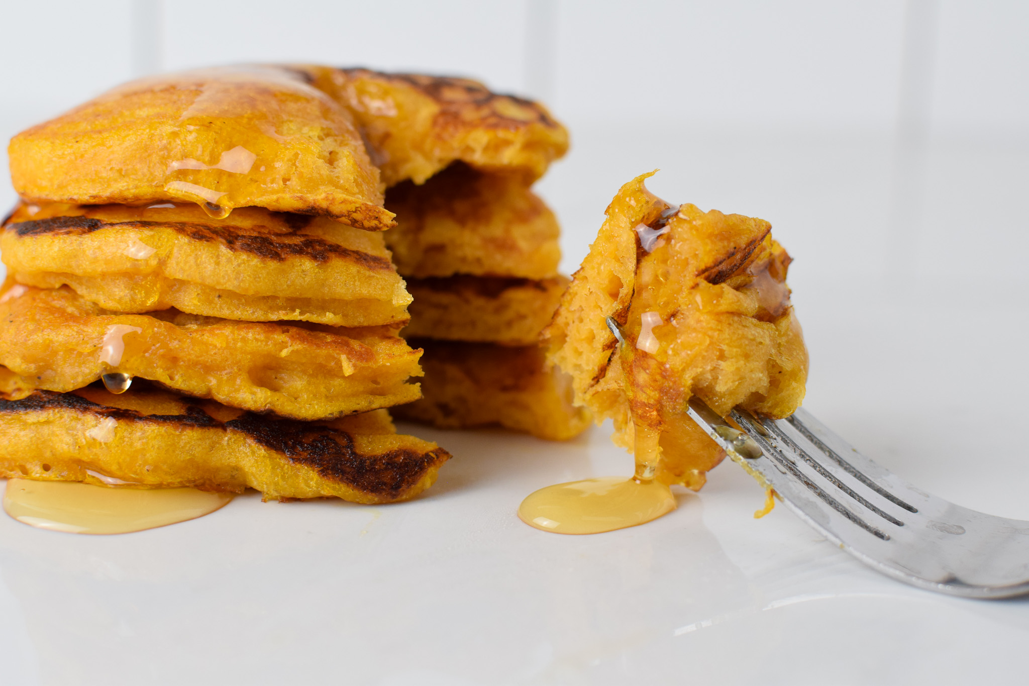 Sourdough Pumpkin Pancakes in a stack with syrup and a fork