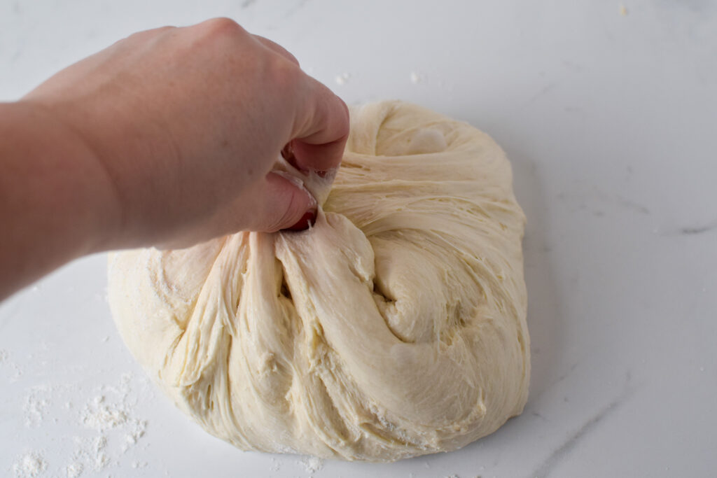 sourdough bread dough on the counter pinched at top by hand