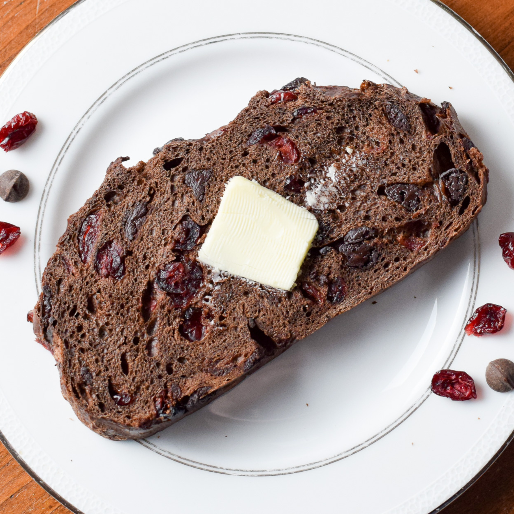 piece of chocolate cranberry bread on a plate with butter