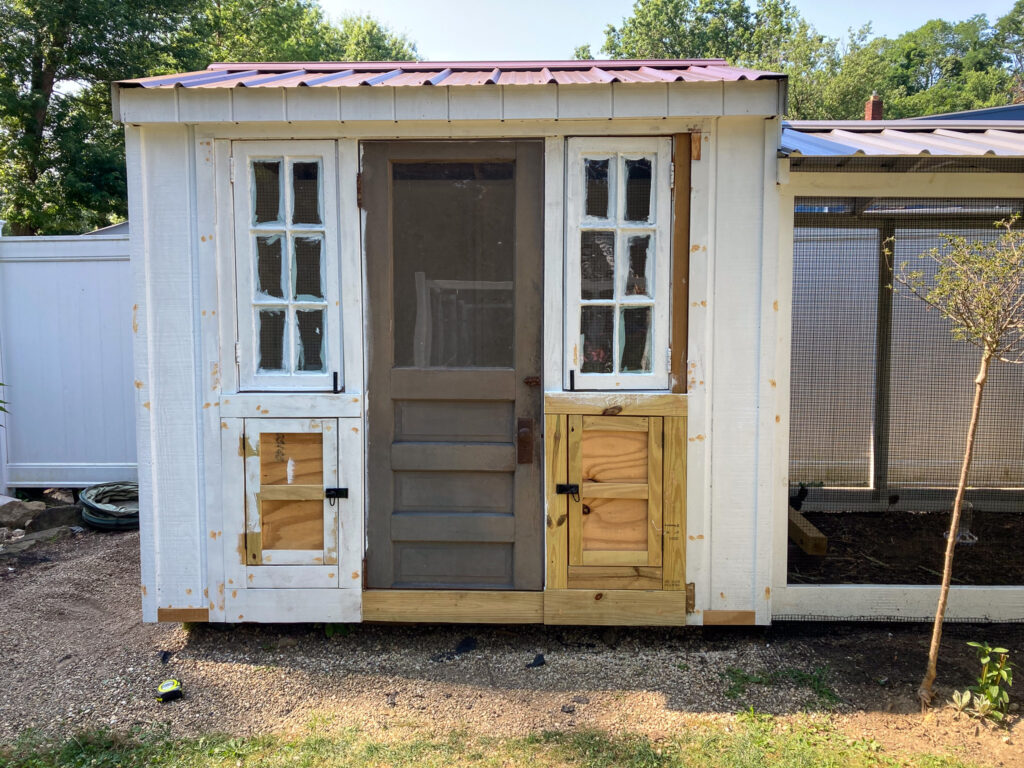 a shed with an added door and window and egg boxes for chickens