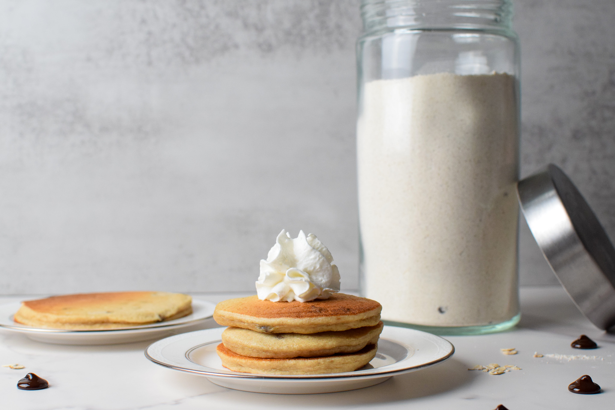 3 pancakes stacked with whipped cream and dry pancake mix in a glass jar